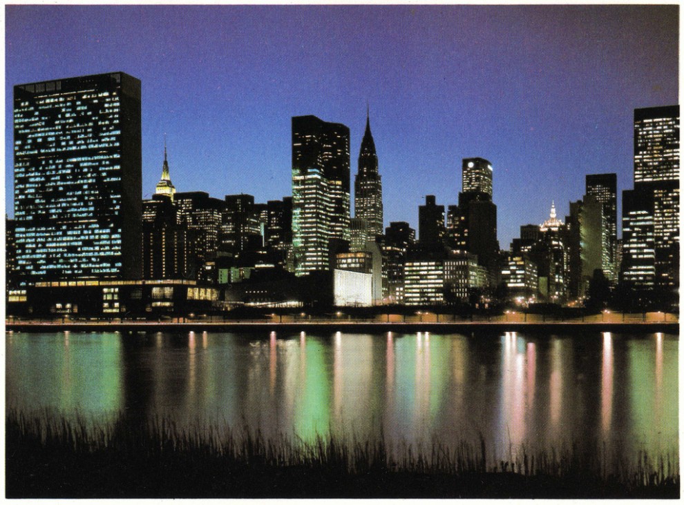 Night view of Midtown Manhattan looking southwest from the East River showing the One United Nations Plaza (center, left to Chrysler Building) completely illuminated. 1979.