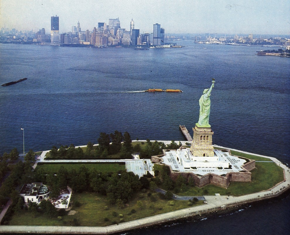 Aerial view of the Statue of Liberty with the new Twin Towers of the World Trade Center beginning to dominate the skyline. May 1970.