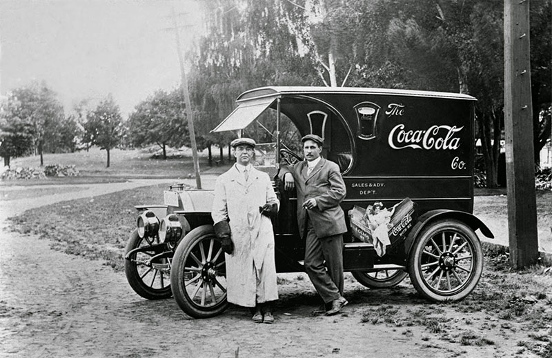 Two man stand in front of a Coca-Cola delivery truck, 1910.